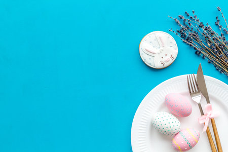 Easter dining table in pastel colors. Plate, cutlery, painted eggs, gingerbread and lavender...