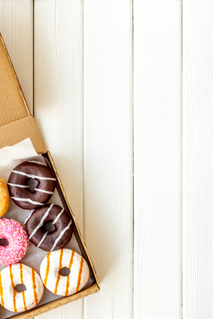 Modern design with donuts in box on white wooden background top view space for text.の写真素材