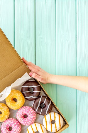 Donuts with different flavors in box on green wooden background top view mockup.の写真素材