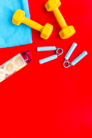 Sport with bars, towel, water and wrist builder on red background top view space for textの写真素材