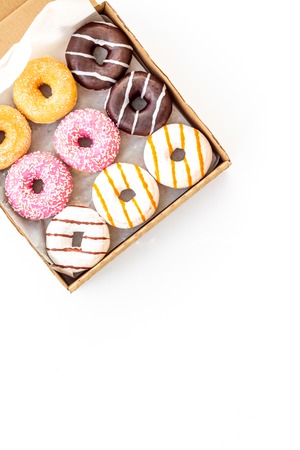 Glazed decorated donuts in box for sweet break on white background flat lay copy space.の写真素材
