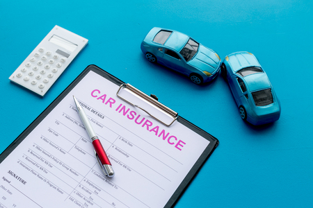 Car insurance concept with form, car toy and calculator on blue desk backgroundの写真素材