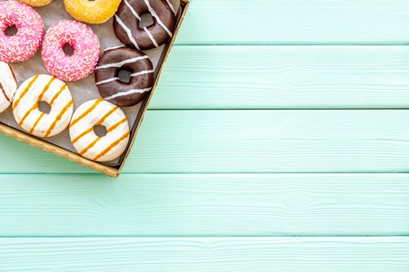 Donuts with different flavors in box on green wooden background top view mockup.の写真素材
