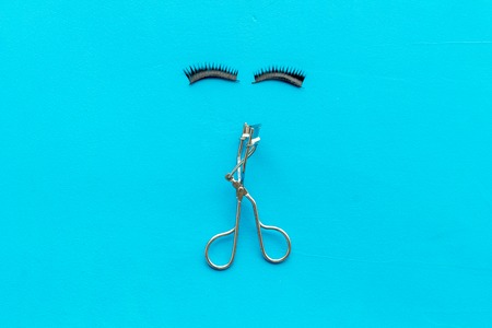 Organic decorative cosmetic set with lash curler on blue woman desk background top view.の写真素材