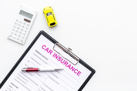 Car insurance concept with form, car toy and calculator on white desk background top view space for textの写真素材