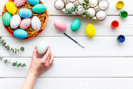 Eggs with colorful paint for Easter tradition on white wooden table background top view mockupの写真素材