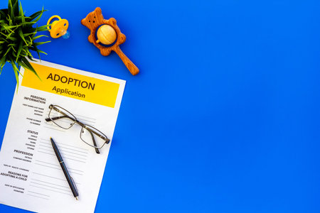 Adoption application, glasses and dummy on blue table background top view copyspace