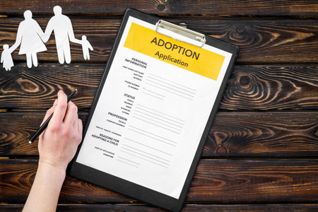 Children care and motherhood set with adoption application and family paper figure on wooden...