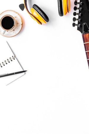 Musician work place with guitar, earphones, notebook and cup of black coffee on white background top view mock upの写真素材