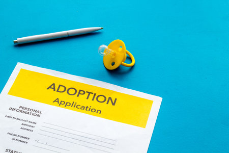Children care with adoption application and dummy on blue office table background