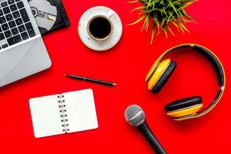 Record studio set. Blogger, journalist or musician work space with microphone, laptop and headphones on red background top view mock upの写真素材