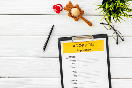 Adoption application, glasses and dummy on white wooden table background top viewの写真素材