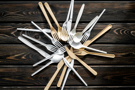 Go green. Plastic flatware, forks, spoons, knifes for eco and Earth protection concept on wooden background top viewの写真素材