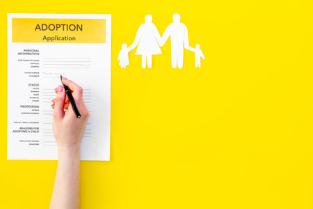 application form for adopt child on yellow background top view mock upの写真素材