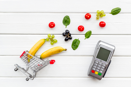Online shopping concept with trolley, card machine near products on white wooden background top viewの写真素材