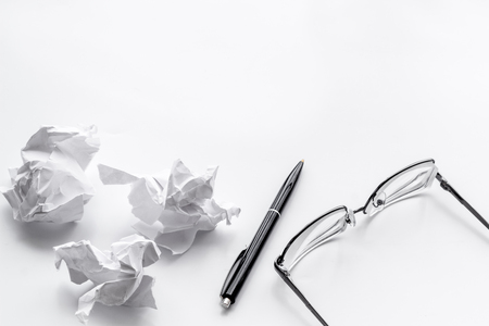 Blogger office desk with glasses, pen and paper balls on white background copyspaceの写真素材