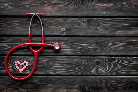 Office desk for doctor. Health care concept. Stethoscope and heart for diagnostic and cure of heart disease on wooden background top view mockupの写真素材