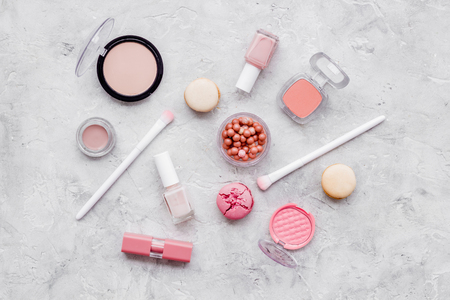 Beauty blogger work. Make-up artist desk with nude powder, blusher,nail polish, decorative cosmetics and macaroon cookies on stone background top viewの写真素材