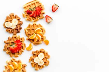 Homemade Viennese waffles with strawberry, tangerine and banana toppings on white background top view mock-upの写真素材