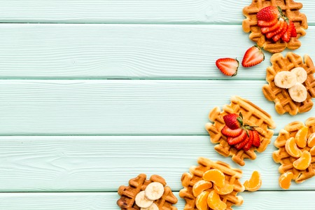 Traditional Belgian waffles with fruit toppings on mint green wooden background top view mock upの写真素材