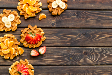 Homemade Viennese waffles with strawberry, tangerine and banana toppings on wooden background top view copy spaceの写真素材