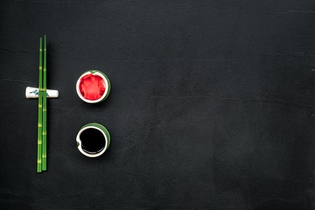 Bamboo sticks, soy sauce, ginger for sushi and maki cooking on black table background top view mockupの写真素材