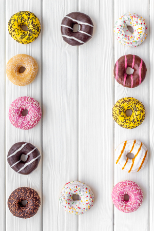 Homemade bakery. Donuts of different flavors for breakfast frame on white wooden background top view space for textの写真素材