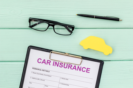 Car insurance concept with form, car toy and glasses on mint green wooden background top viewの写真素材