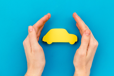 Car insurance concept with car in hands on blue background top view mockupの写真素材