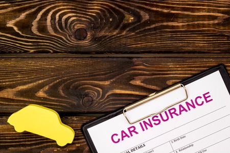 Car insurance concept with form, car toy on wooden background top view mock upの写真素材