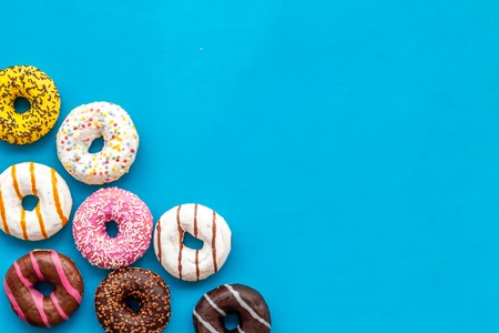Traditional american donuts of different flavors on blue background flat lay mockupの写真素材