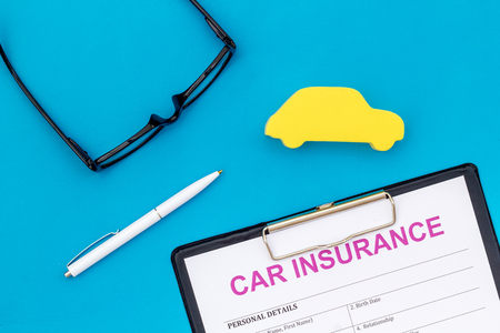 Car insurance concept with form, car toy and glasses on blue background top viewの写真素材