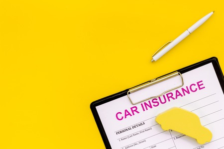 buying new auto concept with insurance form, pen and car toy on yellow background top view space for textの写真素材