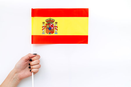 Symbol of the national day of Spain concept with flag in hand on white background top view
