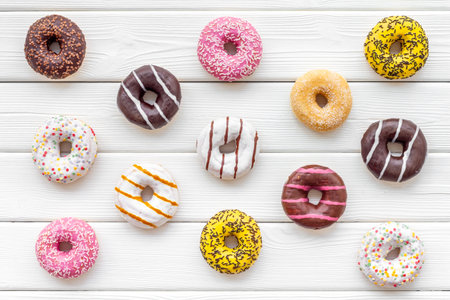Sweet break concept. Traditional american donuts of different flavors on white wooden background...