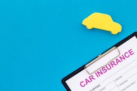 Car buying and insurance concept with car figure and form on blue desk background top view mock upの写真素材