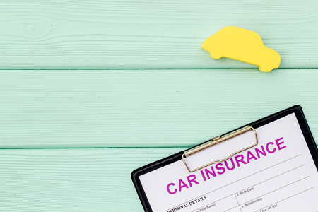 Car buying and insurance concept with car figure and form on mint green wooden desk background top view mockupの写真素材