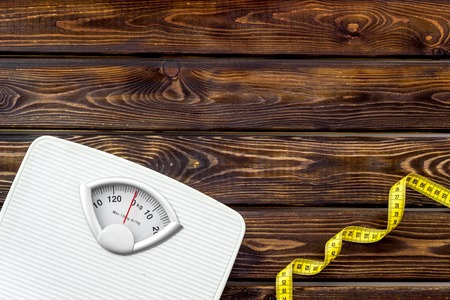 Diet. Bathroom scales and measuring tape for weight loss concept on wooden background top view copy spaceの写真素材
