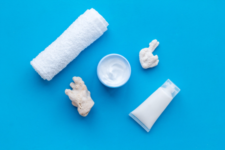Skin care concept. Cosmetics with Dead Sea minerals. Cream, lotion, towel and shells on blue table background top viewの写真素材