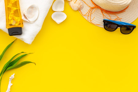 Planning vacation to the seaside with straw hat, sun glasses, sunscreen lotion on yellow background...