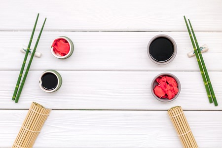 Asian food cooking concept. Oriental table set up with plate and bamboo sticks for sushi and maki, soy sauce and ginger on white wooden background top viewの写真素材