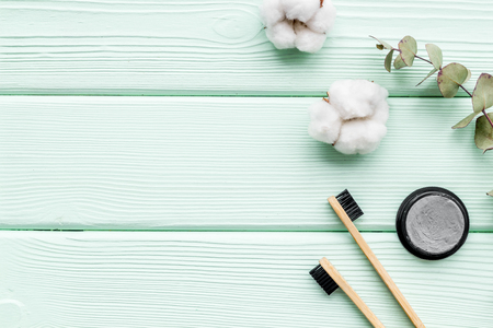 Dental care. Eco materials concept with bamboo tooth brush, toothpaste with bamboo carbon and flowers on mint green wooden background top view mockupの写真素材