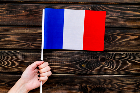 Flag of France in hand on wooden background top view.の写真素材