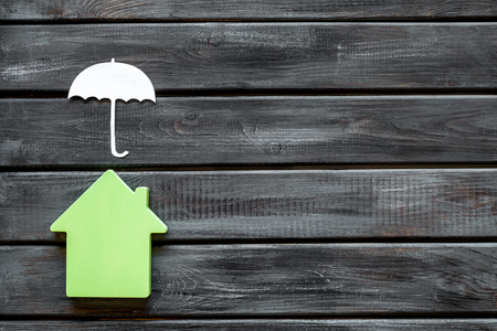 New house purchase. Property insurance concept with house and umbrella toys on wooden background top view mock upの写真素材