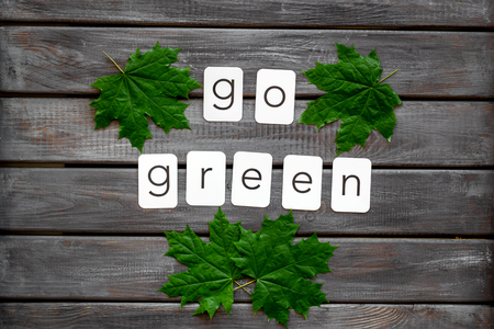 Go green concept with maple leave on wooden background top viewの写真素材