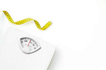 Diet concept with scale and measuring tape for weight loss on white background top view mock upの写真素材