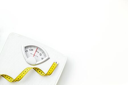 Slim. Medical starvation. Diet concept with scale and measuring tape for weight loss on white background top view mock upの写真素材