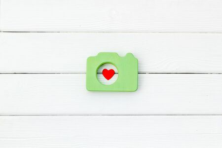 Photo camera concept with heart on white wooden background top view mock up