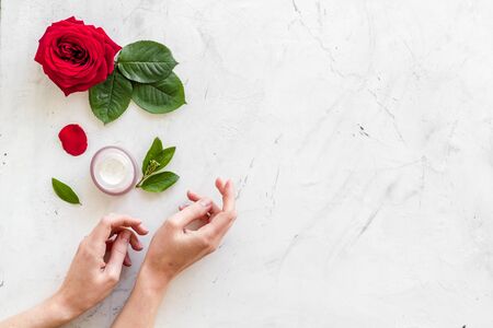 Natural floral cosmetics with rose flowers for face and body care on white marble background top view mock upの写真素材