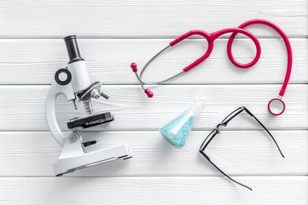 Desk of doctor in laboratory with stethoscope, microscope, pills in test tube for medical research...